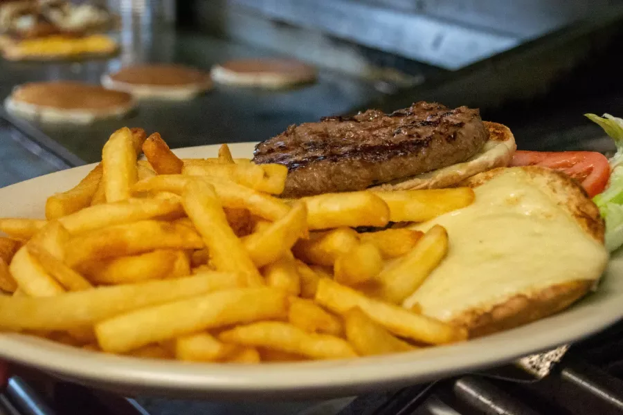 A charbroiled burger with melted cheese and french fries on a diner plate