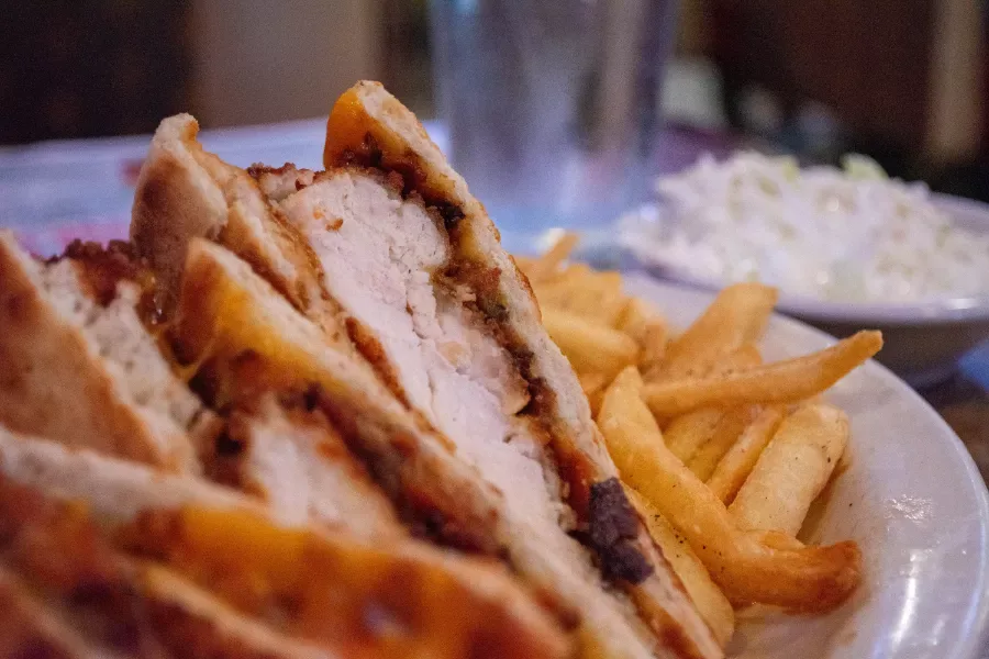 A pressed chicken cutlet panini cut in half, served with french fries and coleslaw